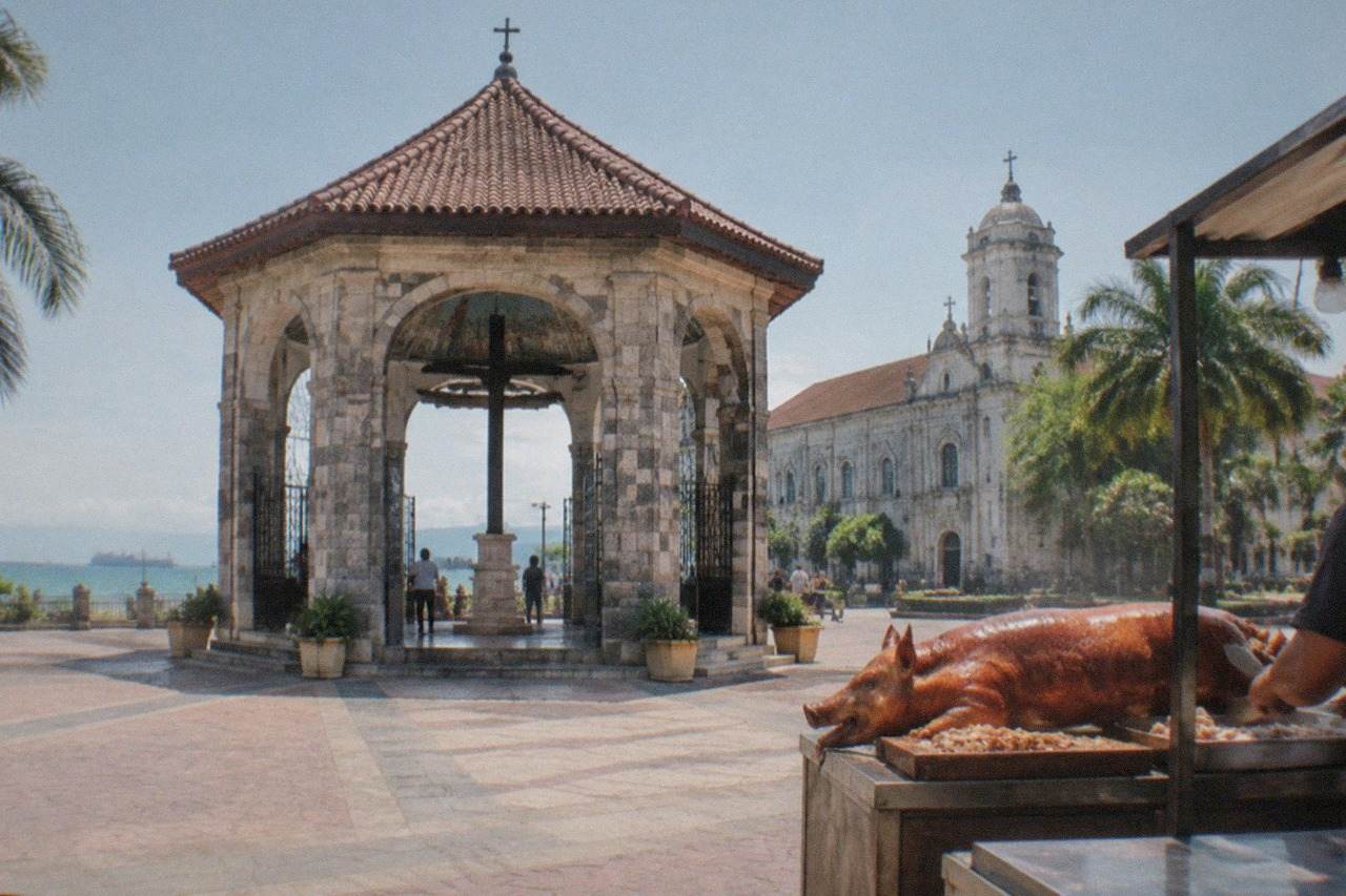 A whole roasted pig with crisp golden skin being carved at a Cebu eatery counter