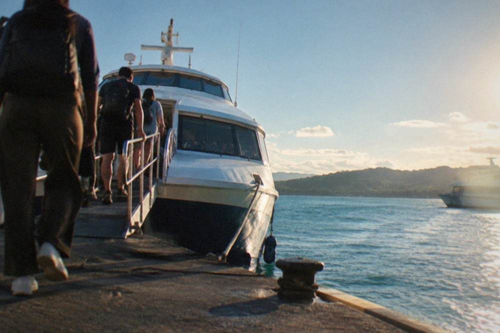 Travellers boarding a white fastcraft ferry at a busy Philippine pier in early morning light