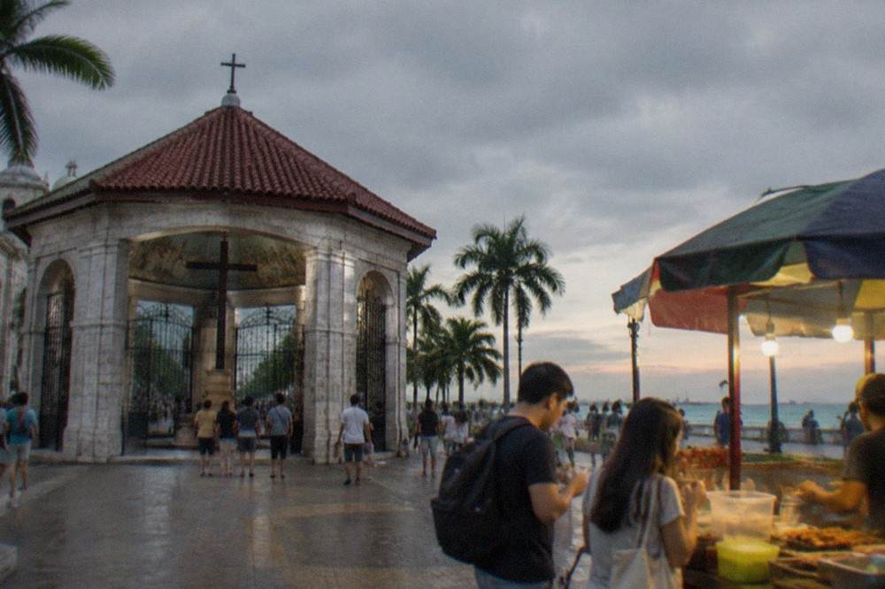 Two people sharing a snack at a busy Cebu street food stall in the evening