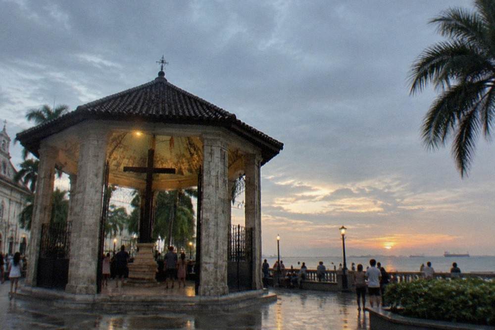 People gathered at an illuminated waterfront promenade in Cebu at dusk