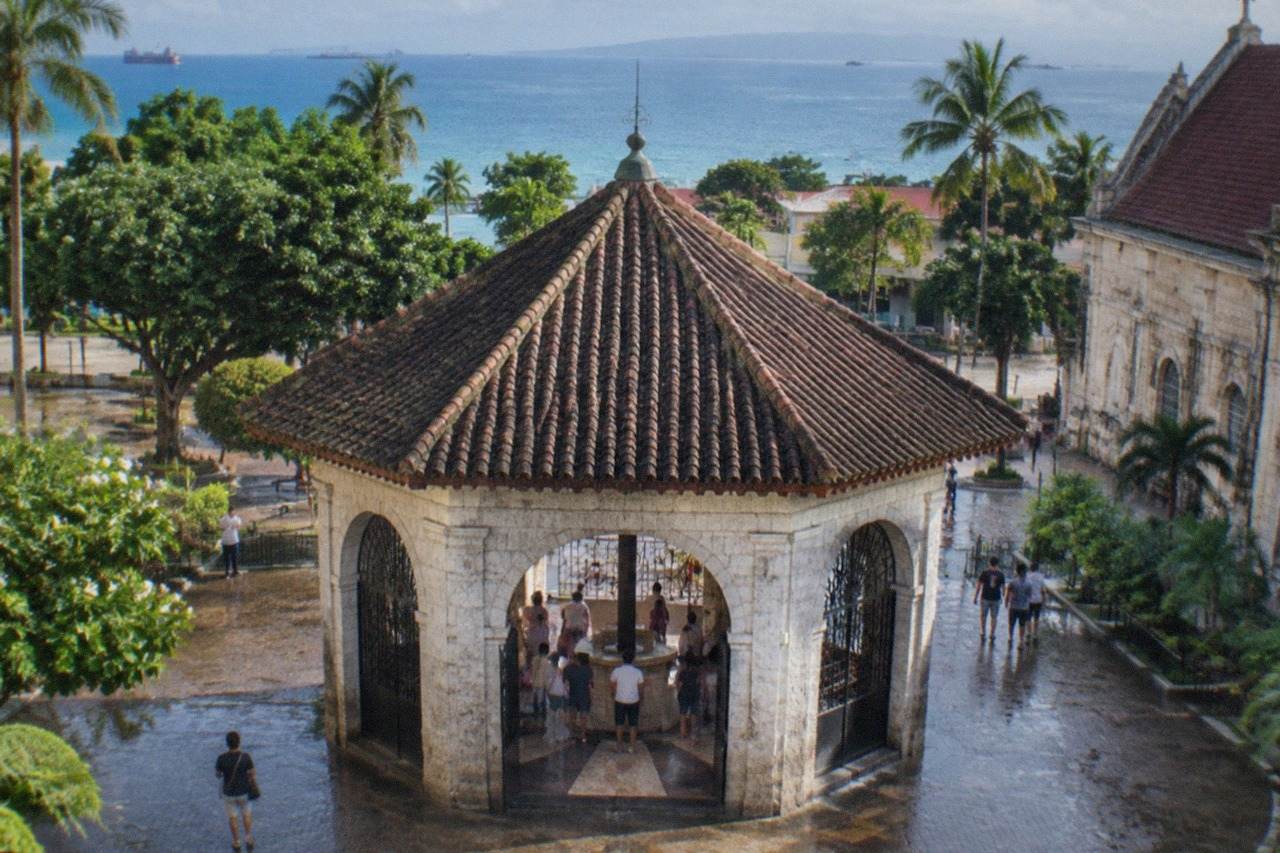 The historic Magellan's Cross pavilion in Cebu City, with visitors gathered under its painted ceiling