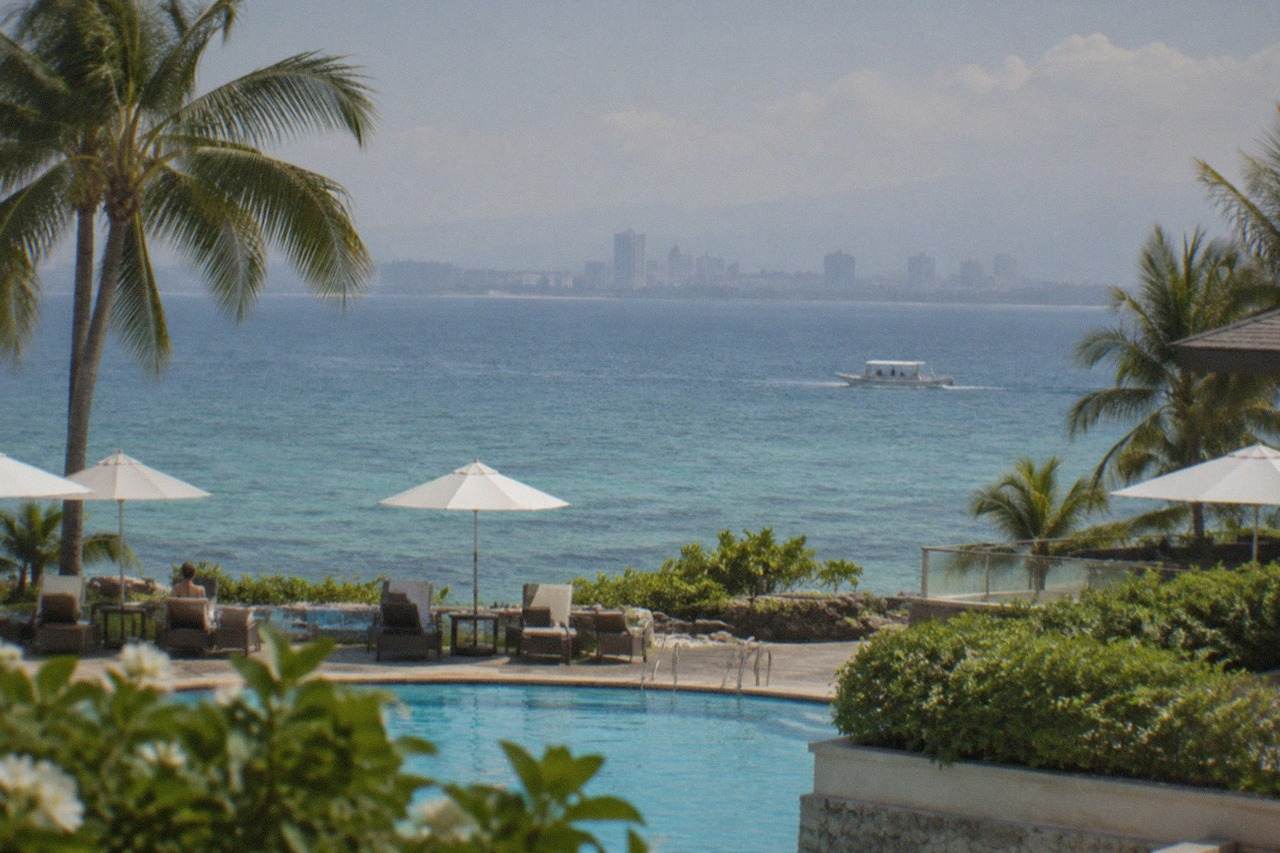 Resort pool deck on Mactan Island overlooking calm turquoise water toward Cebu City across the channel