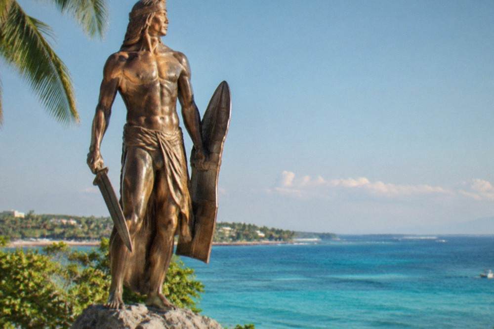 A bronze warrior statue at the Lapu-Lapu Shrine on Mactan Island under a clear morning sky