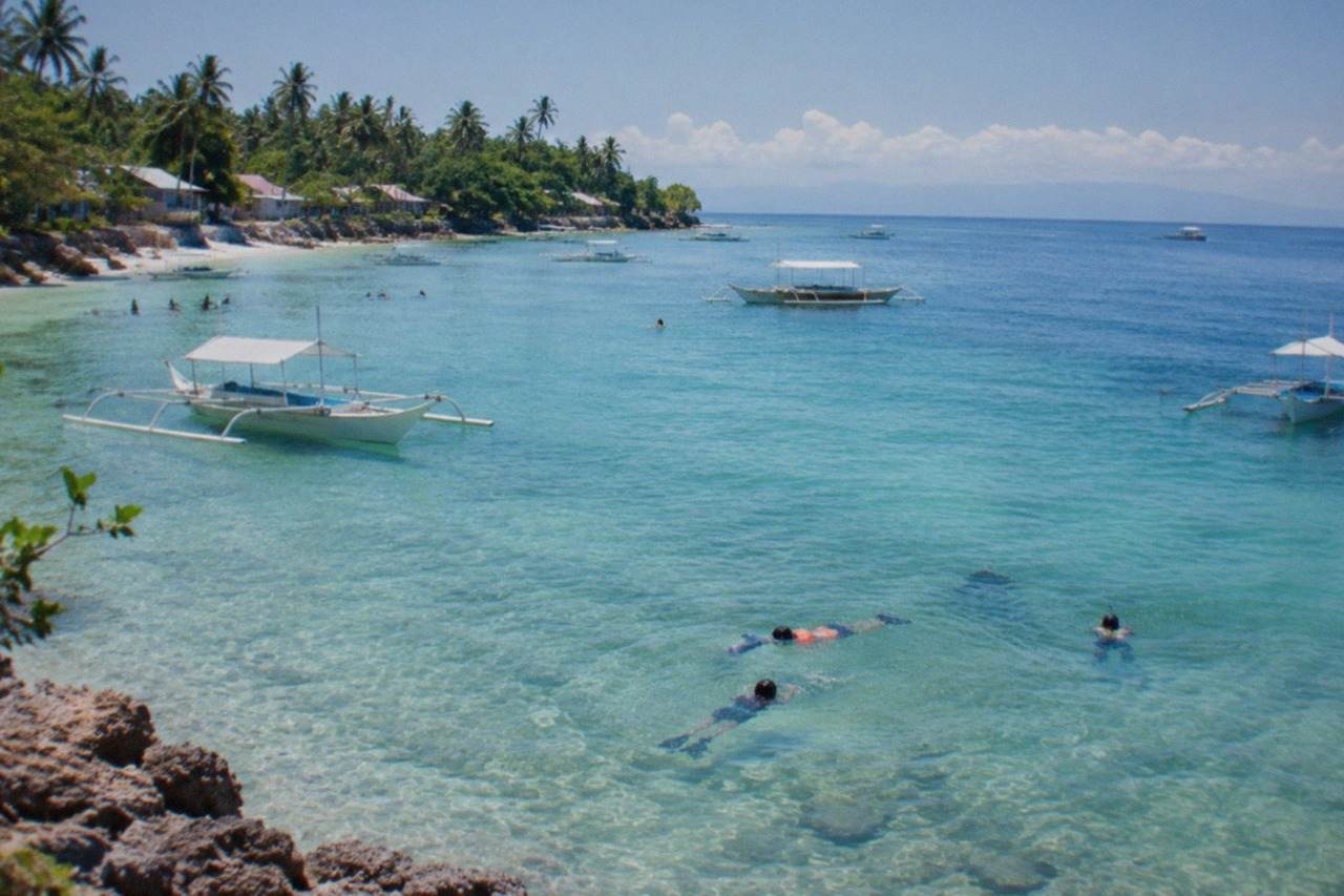 Resort swimming pool and calm turquoise water along the Mactan Channel at sunset