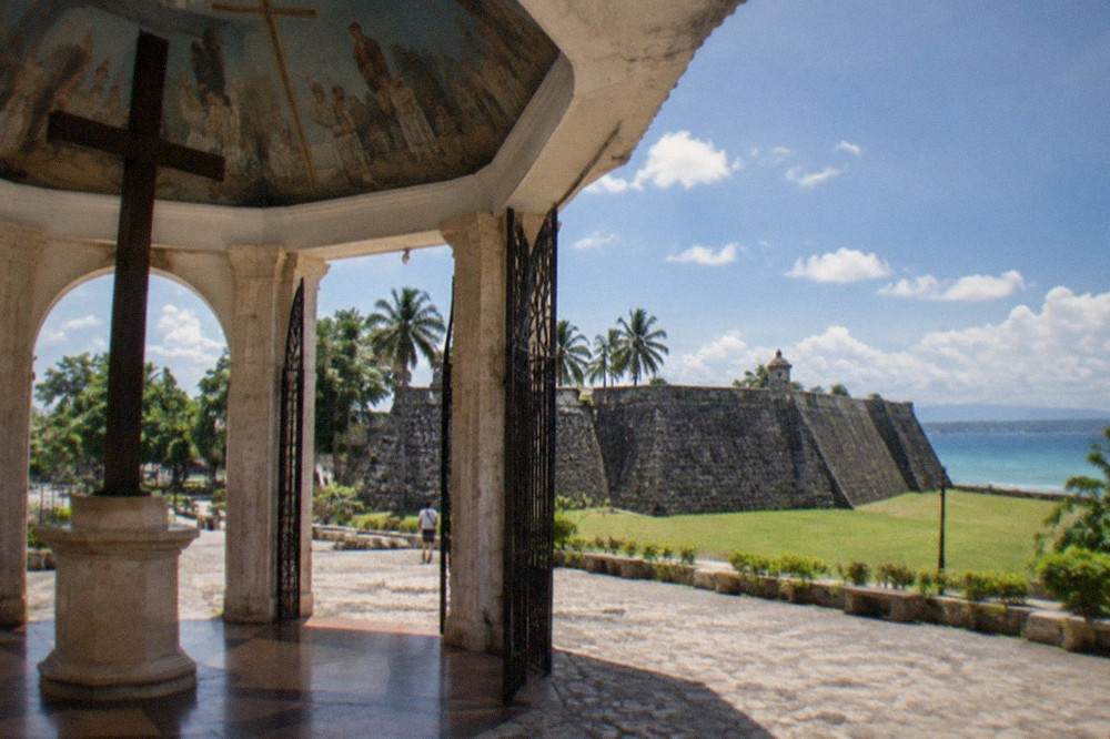 A historic stone fort with triangular walls and a grassy courtyard under a bright sky