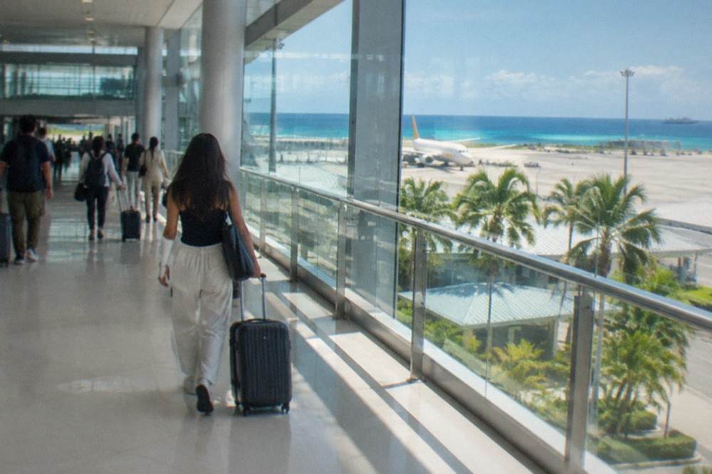 Travelers with luggage walking through a bright modern airport terminal toward arrivals.