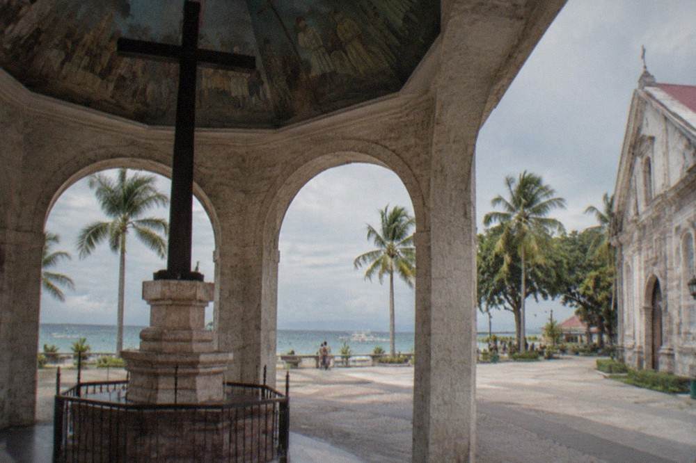 Palm trees and small resort buildings along a quiet beachfront on a Cebu dive-coast town