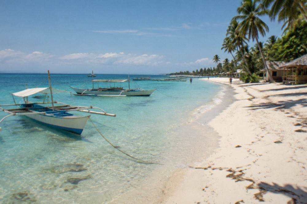 Fishing boats moored in shallow clear water near a Bantayan Island village at midday