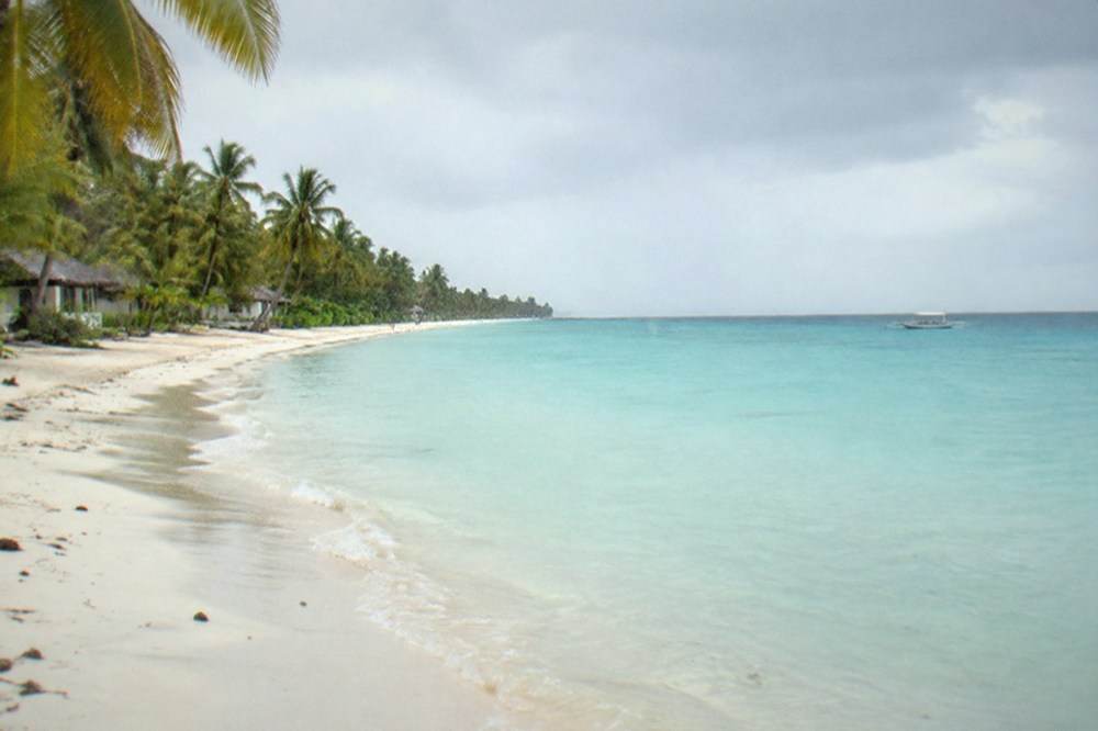 A wide empty stretch of white sand and shallow turquoise water on the Santa Fe coast of Bantayan Island