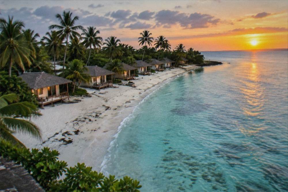A line of small beachfront cottages facing the sunset over shallow water on Bantayan Island