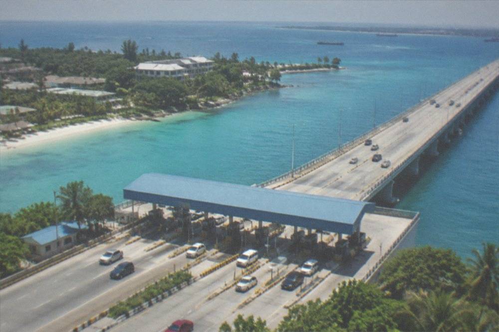 A toll plaza on a long sea bridge with cars passing under gantries