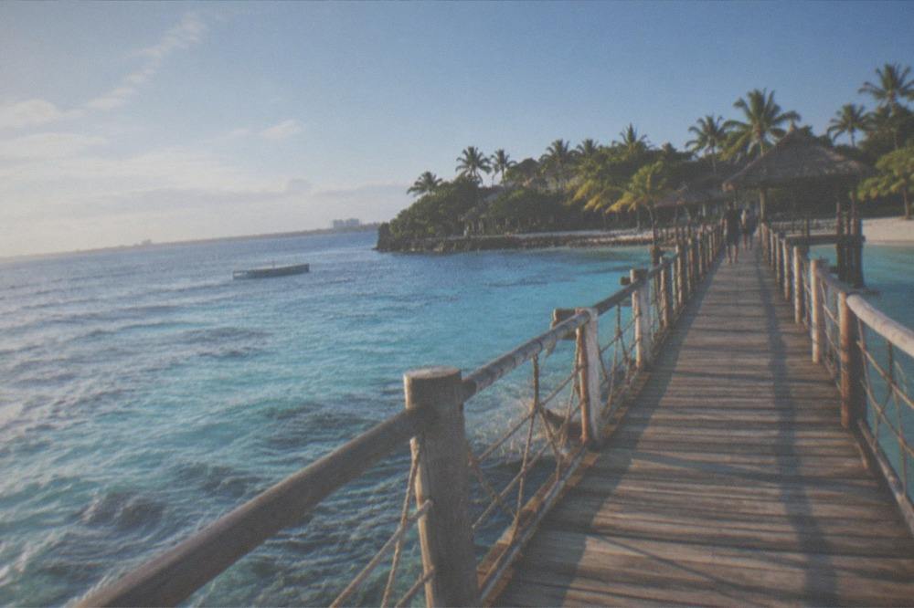 A wooden walkway over shallow water leading to a marine sanctuary area