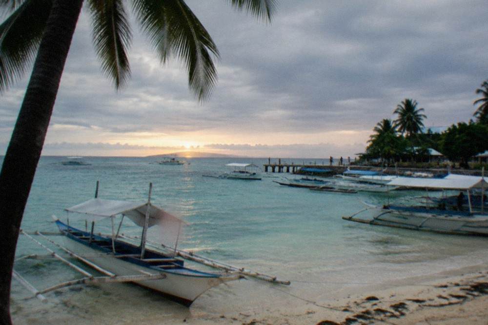 Wooden outrigger boats moored at a small island port at sunrise