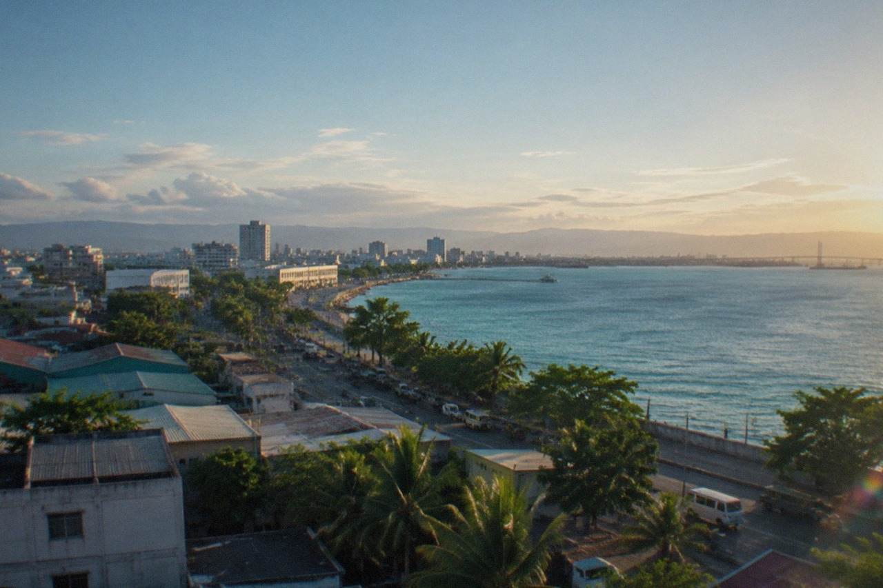 City skyline of Mandaue in Cebu, Philippines, with buildings along the coastal road and the Mactan Channel in the background