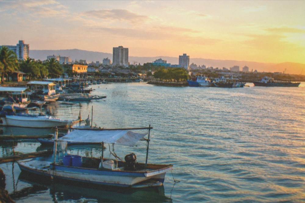 Wide view of the Mandaue river mouth with boats moored along the bank and the city skyline behind them