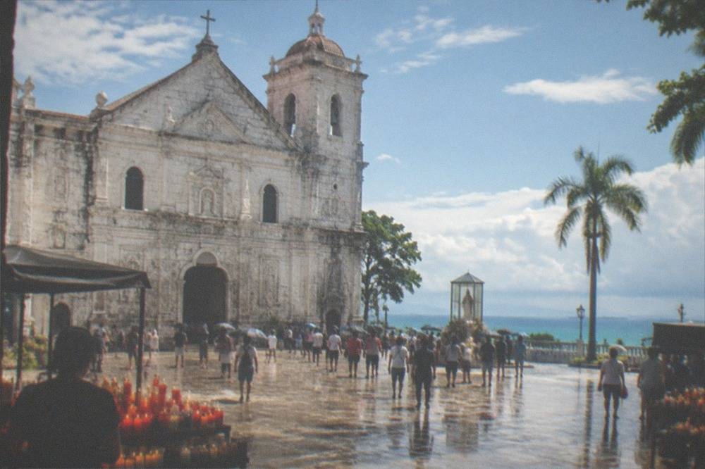 Candle vendors and devotees in the open plaza in front of the Basilica del Santo Nino