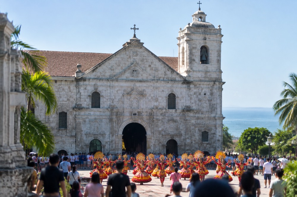 Sinulog dancers in bright costumes performing near the Basilica del Santo Nino during the January festival