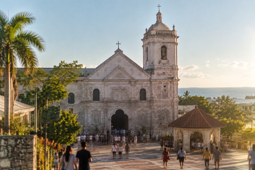 The courtyard and pilgrim center of the Basilica del Santo Nino under a clear tropical sky
