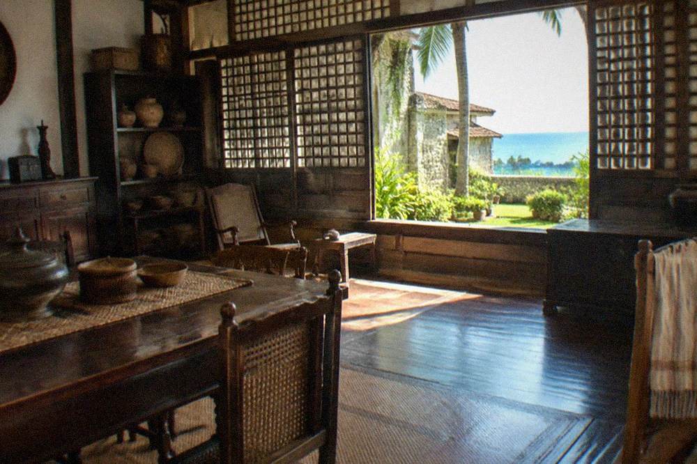 A museum room with antique wooden furniture, woven mats and vintage household items on display