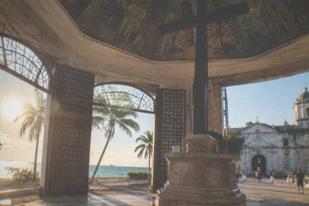 A wide capiz-shell window with wooden shutters open to a street in old Cebu