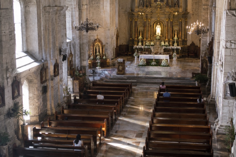 Interior nave of the cathedral with wooden pews and a decorated altar