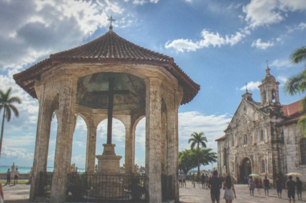 Tourists walking through a heritage plaza near old churches in Cebu City