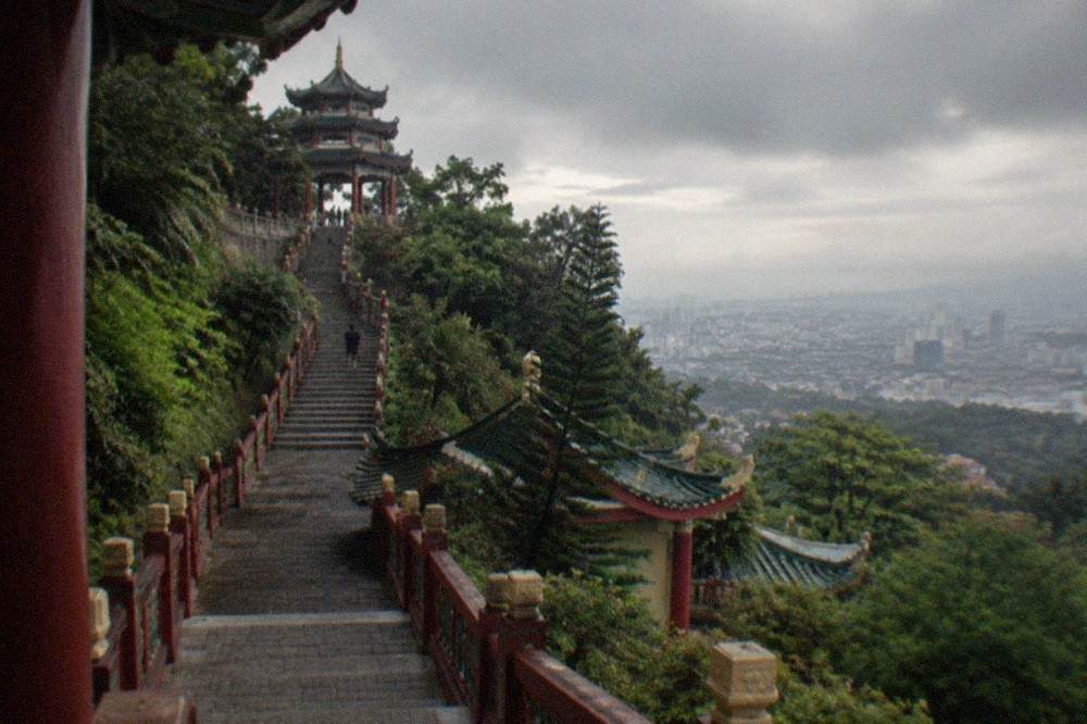 A steep temple staircase with red railings climbing toward a Chinese pagoda roof