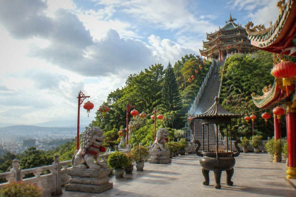 A temple courtyard with red lanterns, stone lions and incense coils