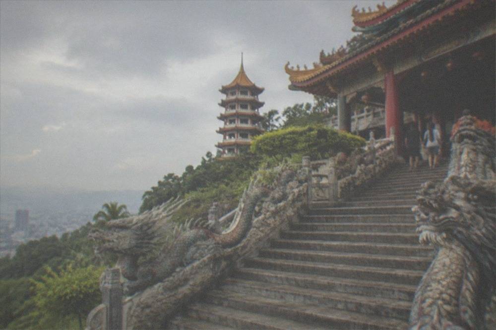 A wide stone staircase with carved dragon balustrades leading up to a red temple building