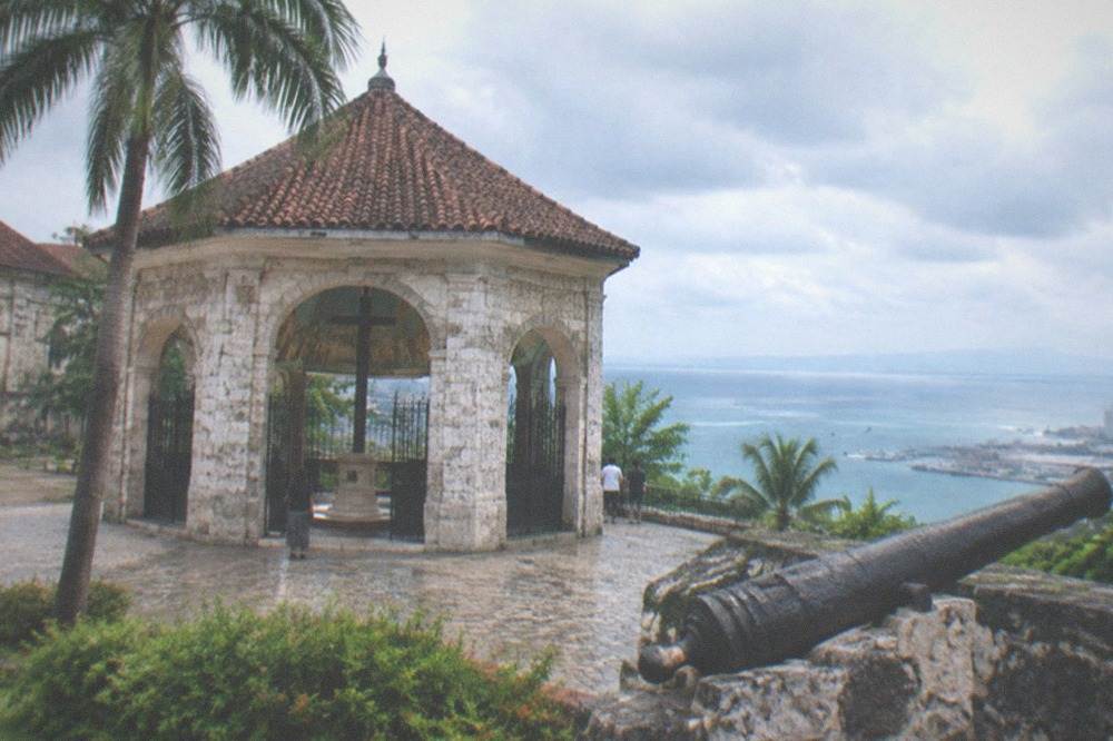 An old cannon mounted on a stone rampart overlooking the port area of Cebu City