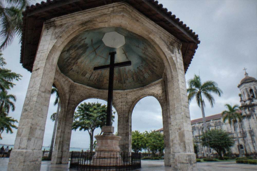 Palm trees and stone walls framing a green courtyard in an old fort in Cebu City