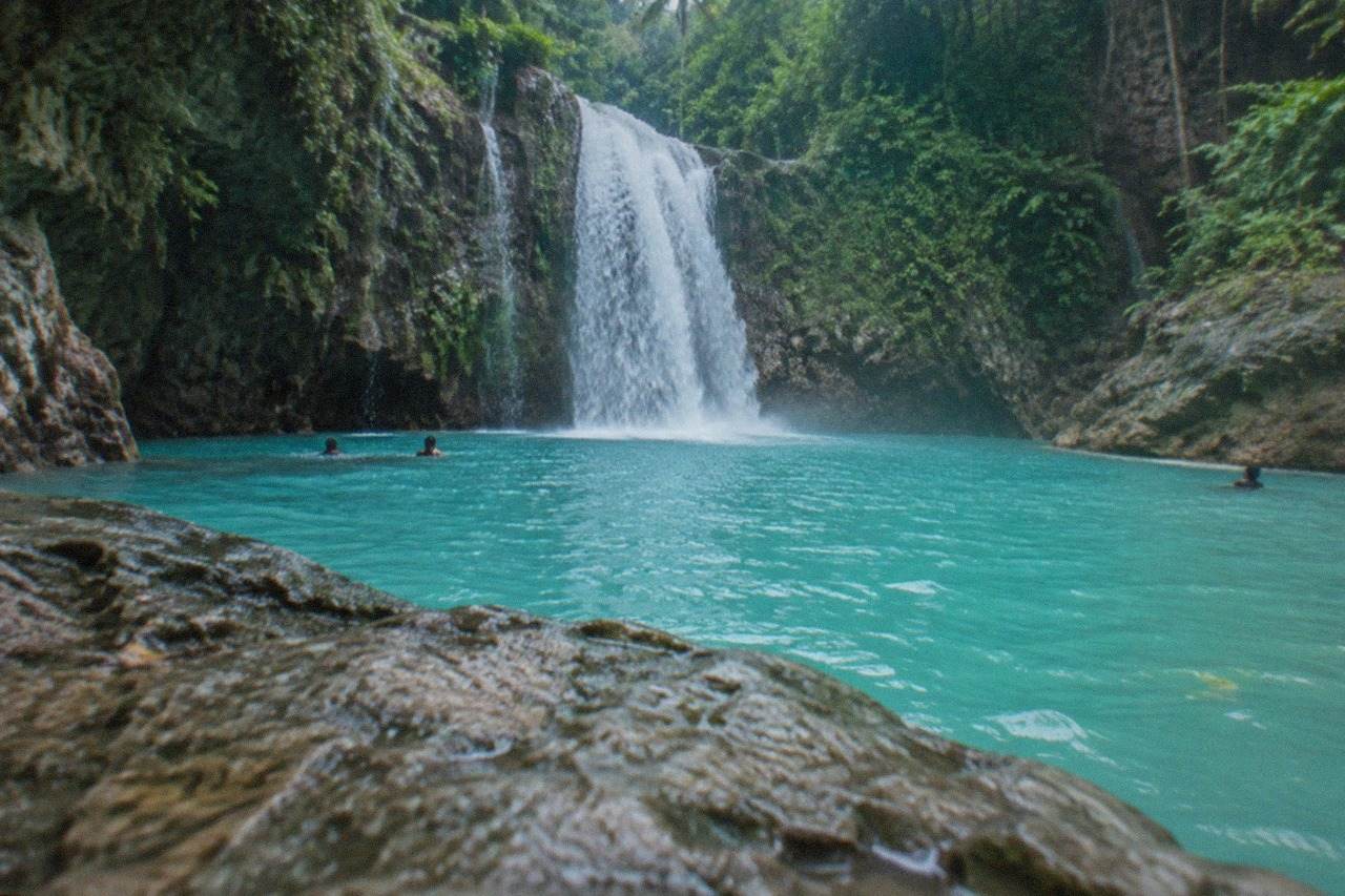 Turquoise waterfall pool at Kawasan Falls surrounded by tropical jungle