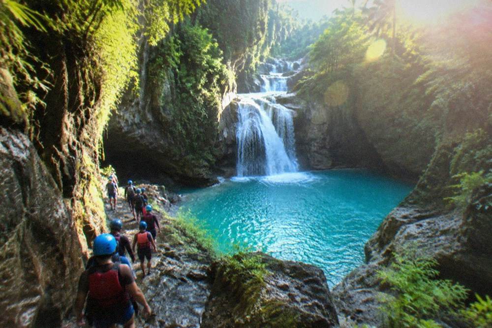 Guided canyoneering group in helmets and life vests walking through a limestone gorge