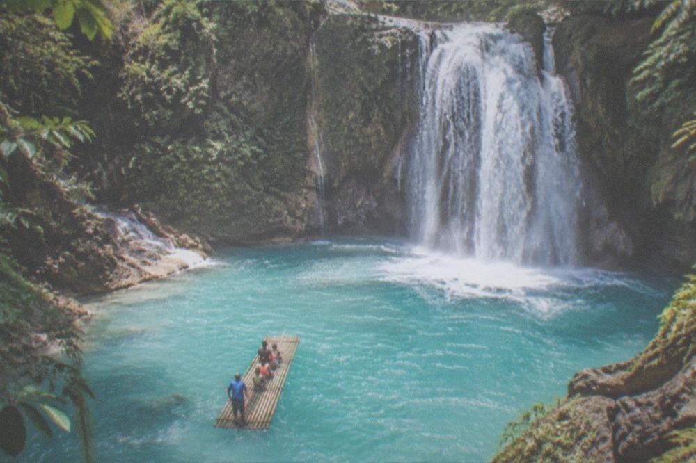 Family on a bamboo raft approaching the main waterfall curtain