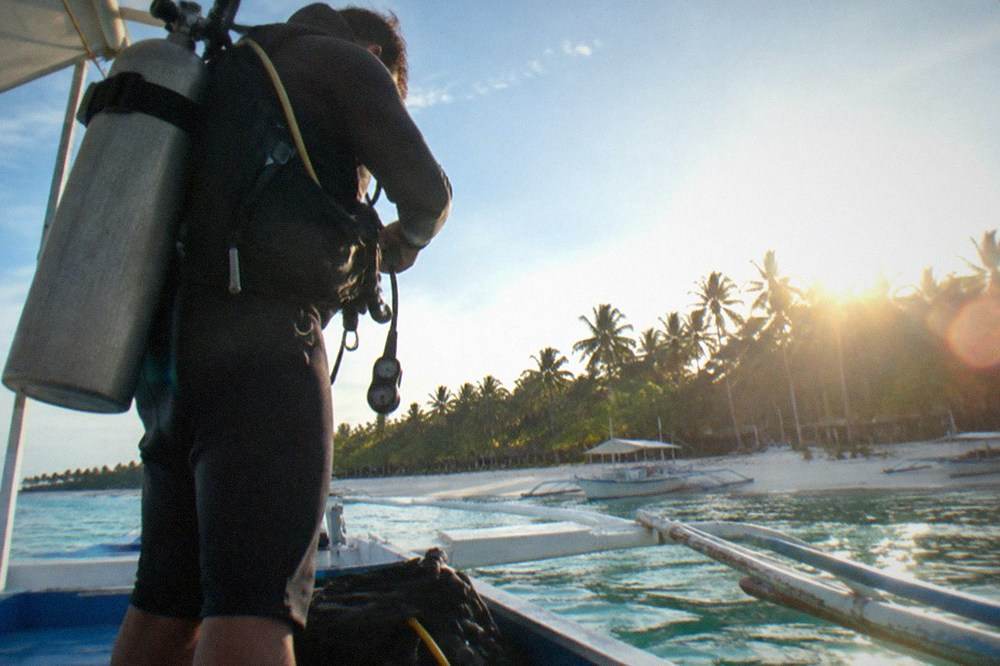 A dive guide checking regulator equipment on a boat before an early morning dive
