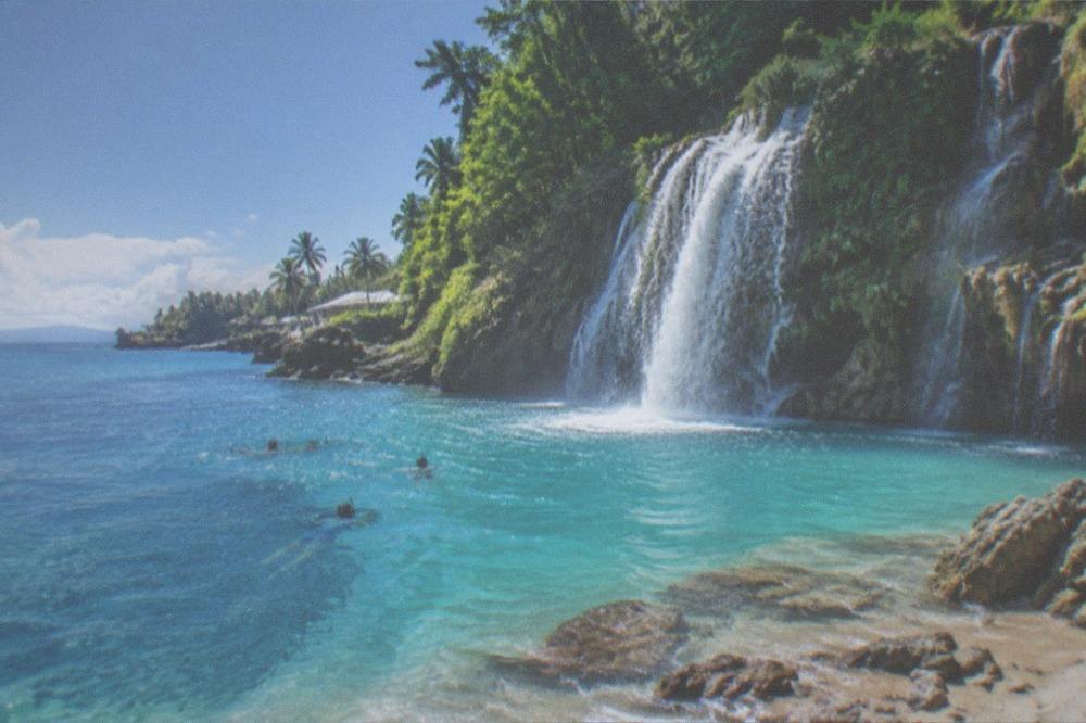 Turquoise water pouring over multi-tiered jungle waterfalls into a natural pool