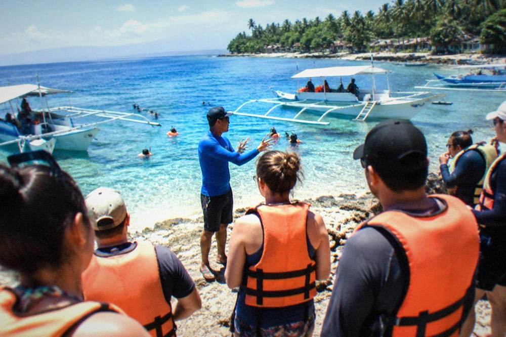 A briefing area with visitors in life vests listening to a guide before boarding boats