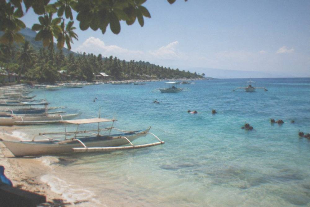 A line of small outrigger boats waiting at a beach at sunrise