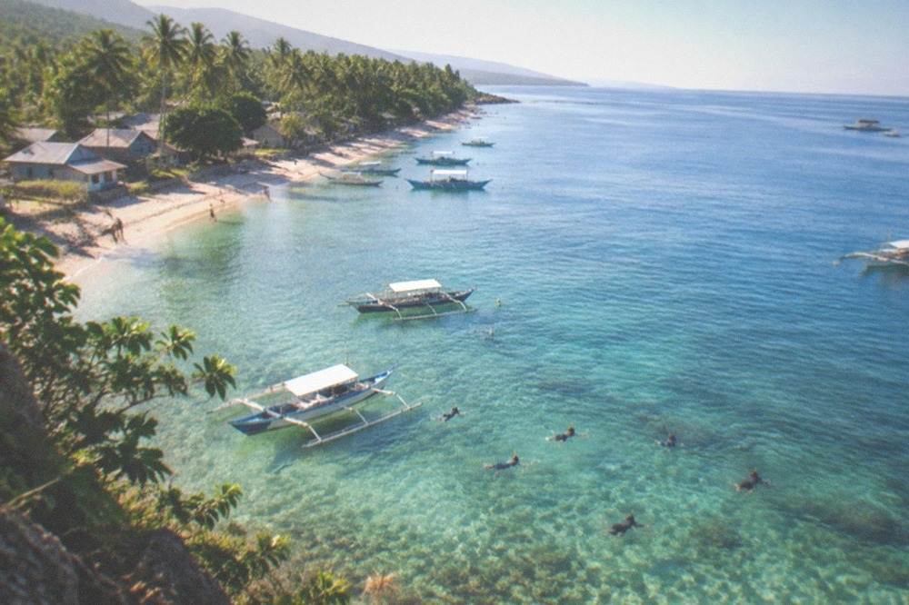 Empty calm water over a shallow reef with boats moored in the distance