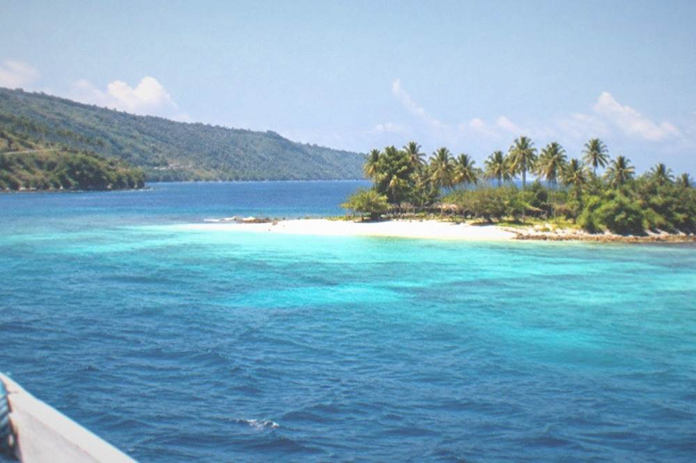 A highway along a tropical coast with green hills and blue sea on the horizon