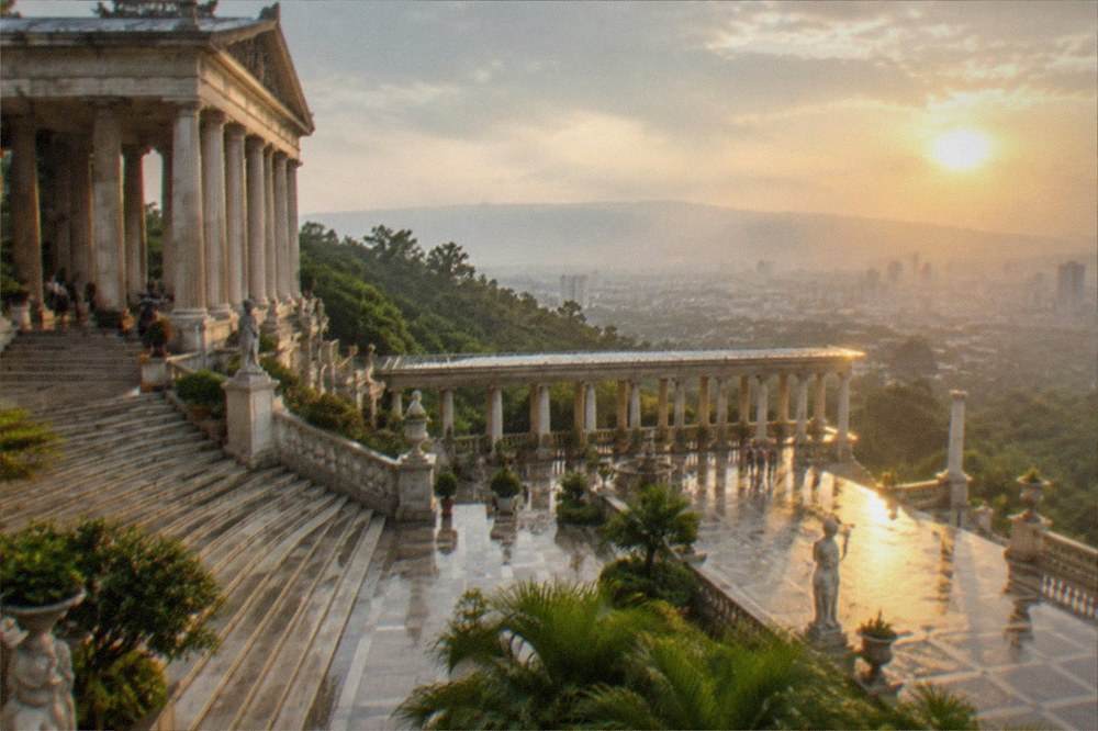 A stone temple terrace glowing in golden late afternoon light above a hazy city skyline
