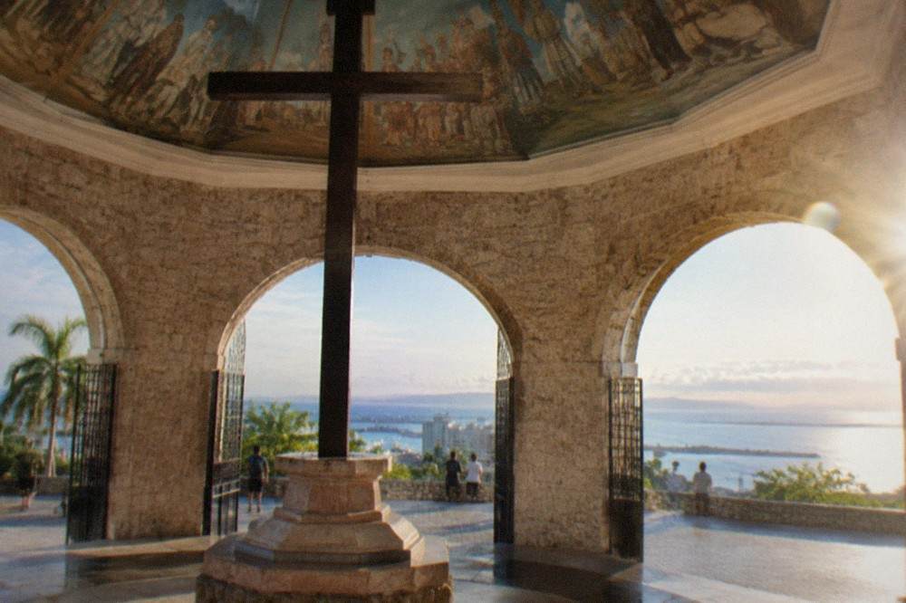 Circular concrete viewing platform on a ridge with a panoramic view over a tropical city and sea in daylight
