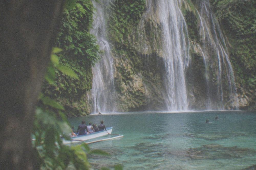 A small open boat with snorkelers moving over calm early morning water near a reef