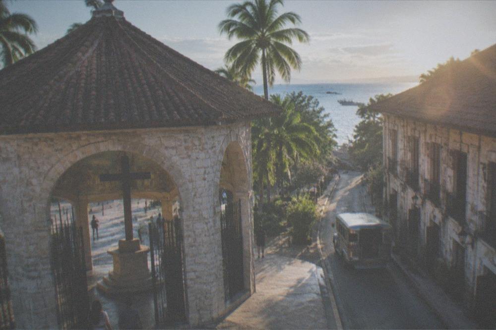 A narrow street in old Cebu City with a jeepney passing colonial-era buildings
