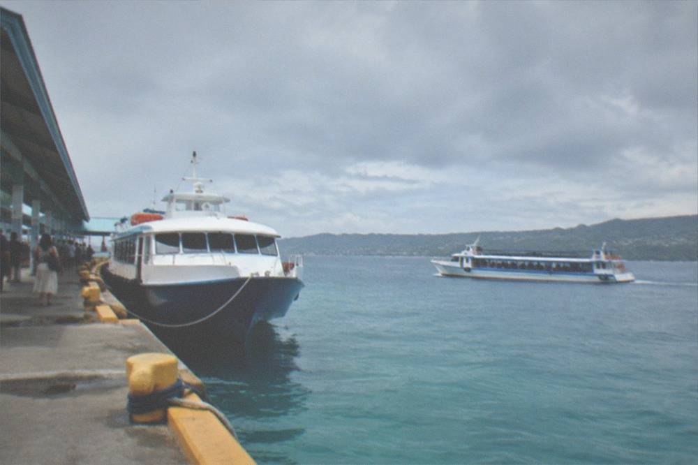 A flat-bottomed buffet boat cruising on the green Loboc River between palm-lined banks in Bohol
