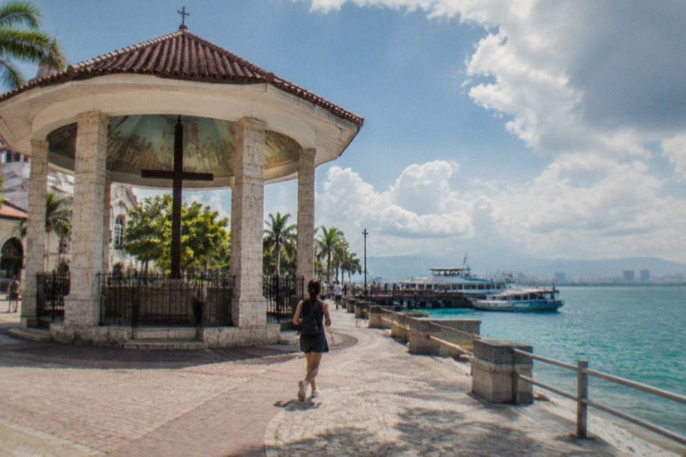A ferry terminal pier with passenger boats moored along a waterfront at midday