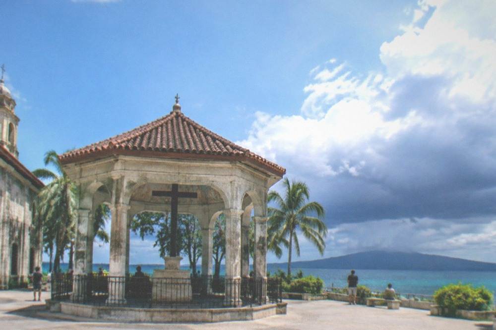 Dark storm clouds gathering over a calm tropical sea with a distant island silhouette
