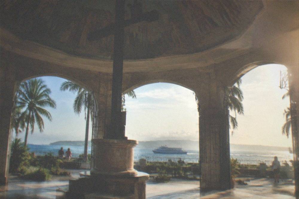 A passenger ferry crossing open water toward green low-lying islands on the horizon