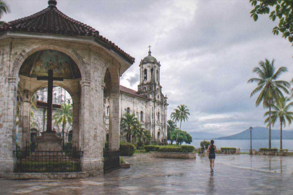 A quiet freshwater lake surrounded by coconut palms and green hills