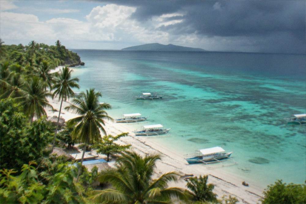 Dark storm clouds gathering over a calm tropical sea with an island on the horizon